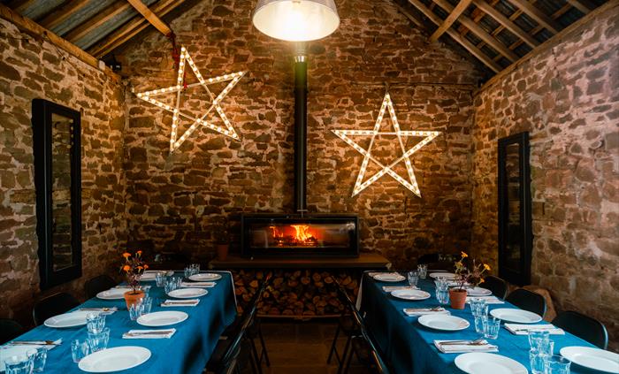Internal image of stone barn with 2 tables laid for dining
